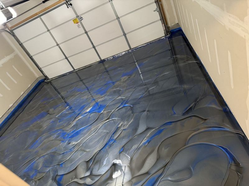 Blue and silver metallic epoxy flowing across a garage floor during install in Joliet, IL