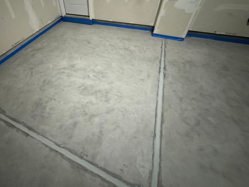 Freshly ground bare concrete garage floor with crack-sealed joints and taped borders, ready for epoxy, Joliet, IL
